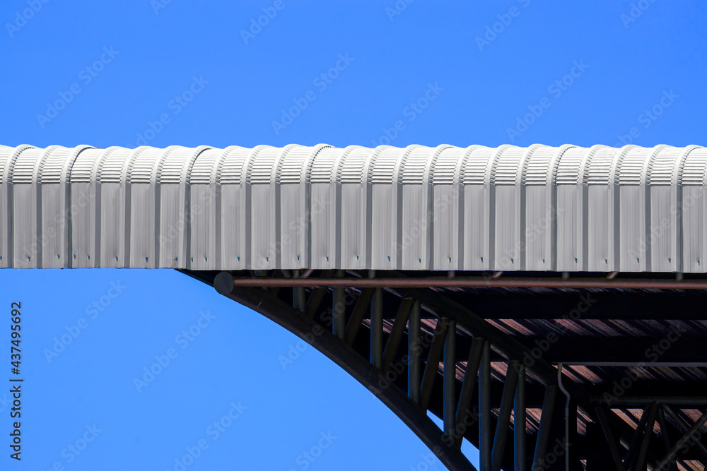 Curved steel roof crimp with black metal roof structure against blue clear sky background