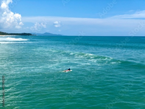 A young man surfer riding waves at Natai beach in Phang Nga, Thailand. Asian man catching waves in blue ocean. Surfing action water board sport. © Belezapoy