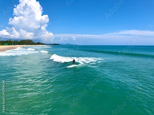 A young man surfer riding waves at Natai beach in Phang Nga  Thailand. Asian man catching waves in blue ocean. Surfing action water board sport.