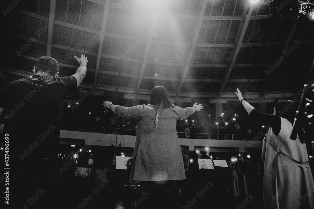 Christians raising their hands in praise and worship at a night music concert - obrazy, fototapety, plakaty 