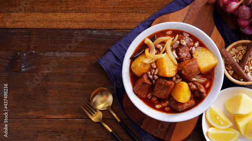 Thai food with rice Pork massaman curry with potatoes, peanuts, coconut milk and onions in a cup on a wooden table