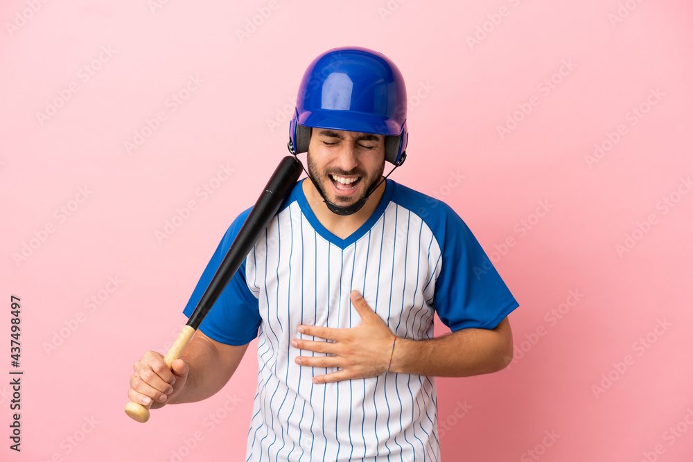 Baseball player with helmet and bat isolated on pink background smiling a lot Baseball player with helmet and bat isolated on pink background smiling a lot