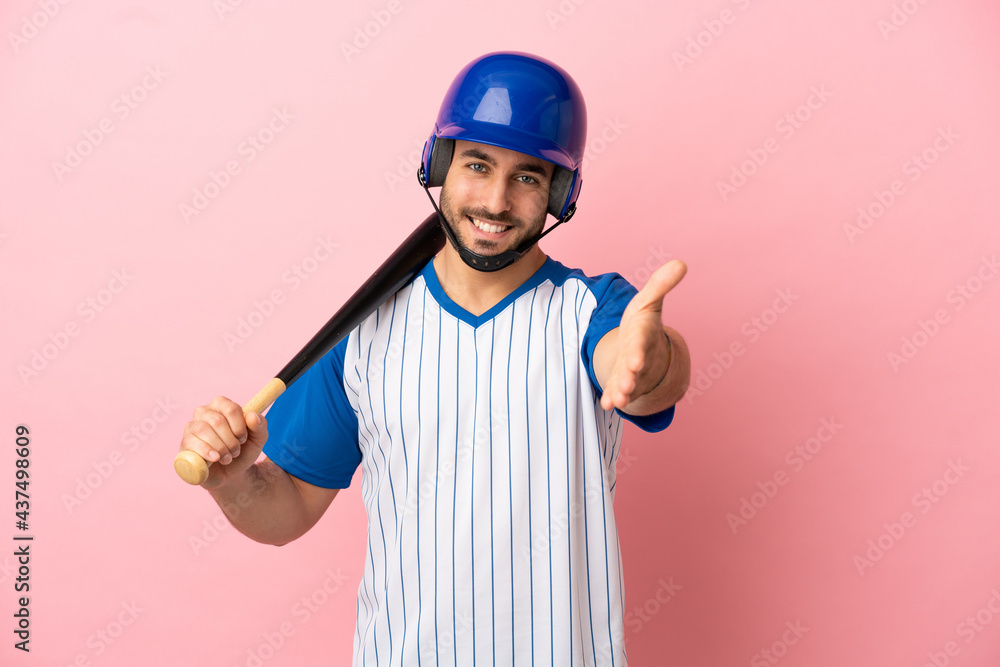 Baseball player with helmet and bat isolated on pink background shaking hands for closing a good deal