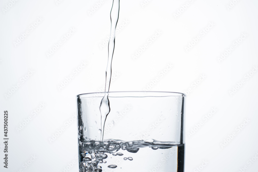 Jet of water or alcohol is pouring into a glass with splashes and bubbles, copy space Jet of water or alcohol is pouring into a glass with splashes and bubbles, copy space