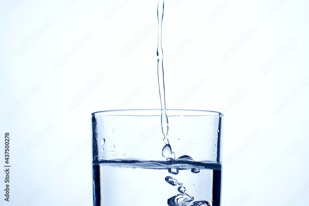 Jet of water or alcohol is pouring into a glass with splashes and bubbles, copy space Jet of water or alcohol is pouring into a glass with splashes and bubbles, copy space
