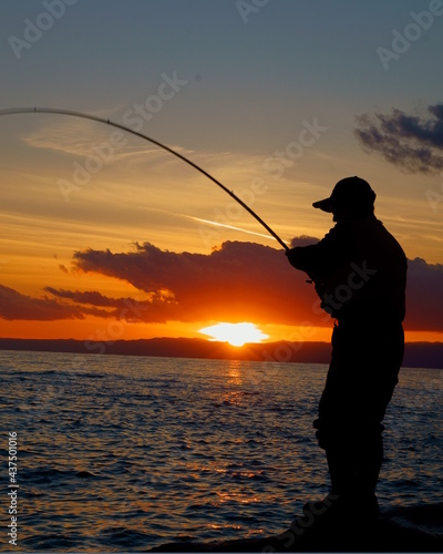 夕方に魚を釣る人のシルエット