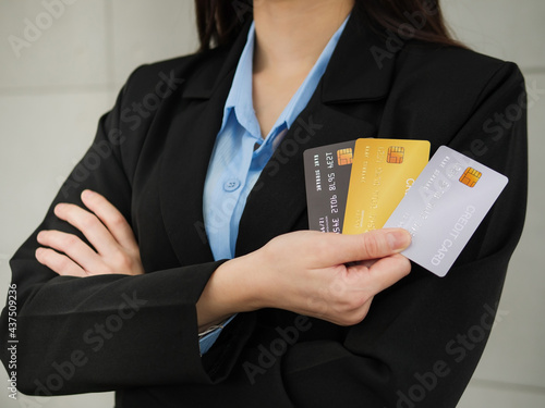 Close-up of three mockup credit cards in a businesswoman's hands, a businesswoman in a black suit with arms closed is holding three mockup credit cards in her right hand.