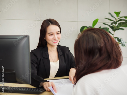 A beautiful manager with a smiling face is talking with a coworker in the office. Two businesswomen are talking in the office