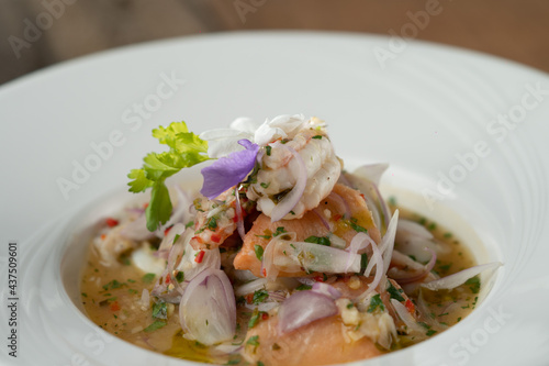 Prawns, white snapper, squid, salmon in a spicy orange dressing isolated on the wooden table