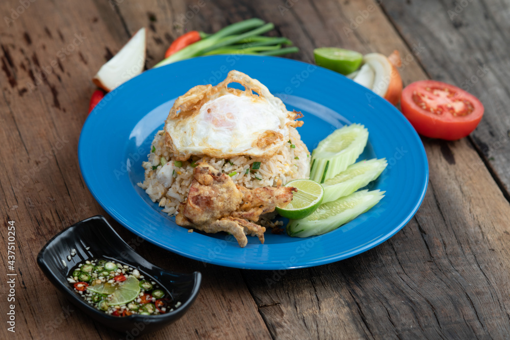 Fried rice with egg on top, pork crackling and cucumber isolated on rustic wooden table Fried rice with egg on top, pork crackling and cucumber isolated on rustic wooden table