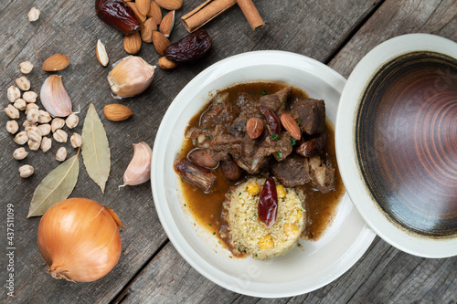 Slow cooked lamb with potato and dates served with warm couscous and chickpeas isolated on the wooden table