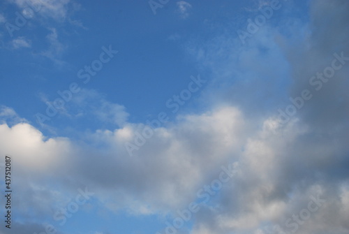 Multilevel clouds in the sky. In the light blue sky, clouds of different shapes and in different layers. Part of the clouds is white, part is gray from the shadow falling on them.