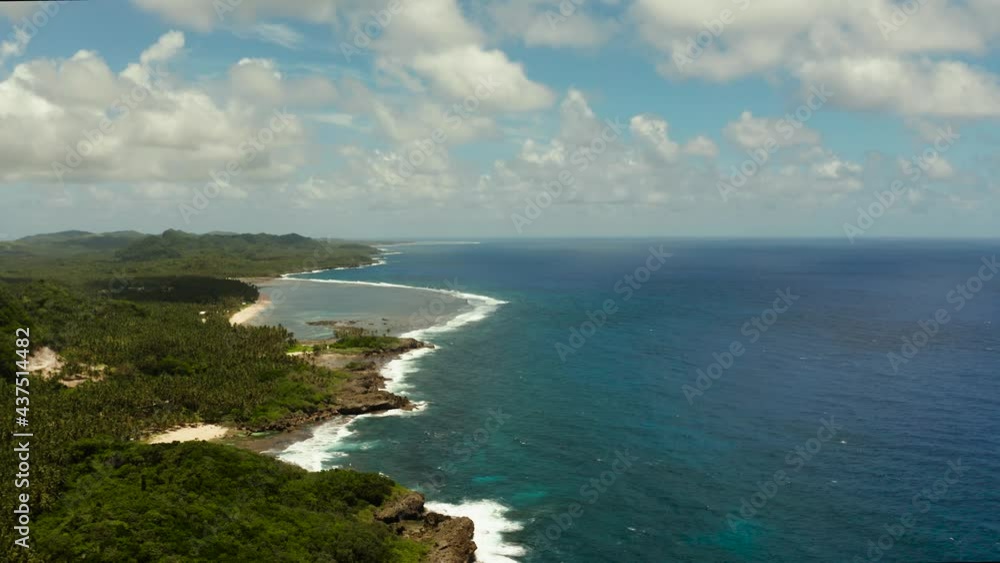 Seascape with the coast of the tropical island covered with forest and palm trees against the sky and blue water. Siargao,Philippines Seascape with the coast of the tropical island covered with forest and palm trees against the sky and blue water. Siargao,Philippines