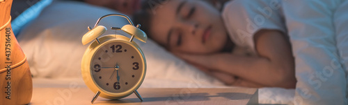 The alarm clock on the background of the sleeping family. night time