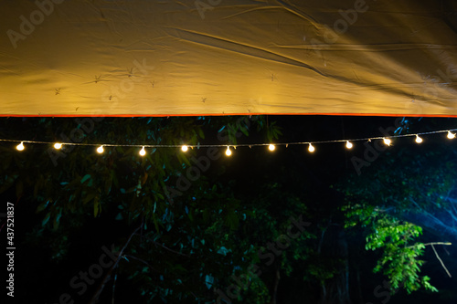 Beautiful rows of bulb lamps at camping  lamp on dark background  Yellow mini lamp  tent lighting..