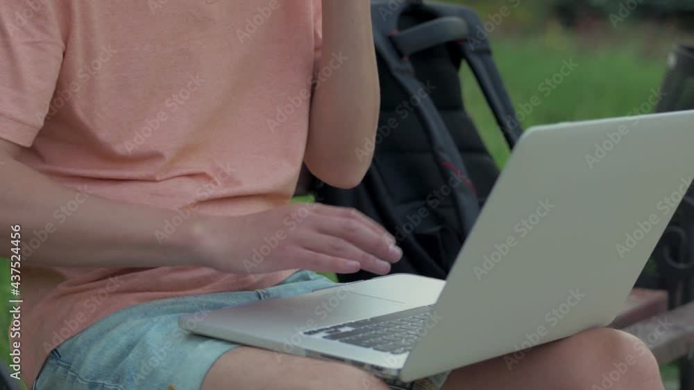 A man using a laptop and talking on the phone while sitting in a city park. A man using a laptop and talking on the phone while sitting in a city park.