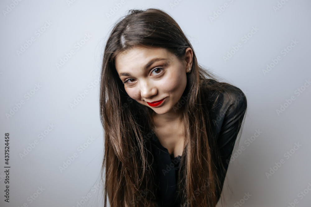 Beautiful girl with red lips looking at the camera. Close-up portrait on a light gray background. Beautiful girl with red lips looking at the camera. Close-up portrait on a light gray background.