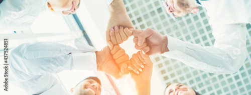 The four happy business people greeting with a fist on the sunny background