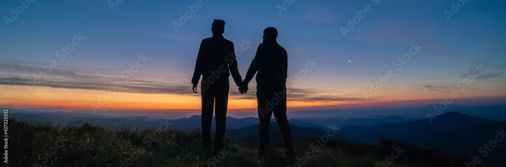Fototapeta premium The silhouette of the couple on the mountain sunset background
