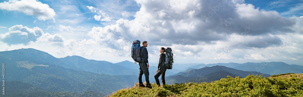 The man and a woman on the mountain on the picturesque cloudscape background
