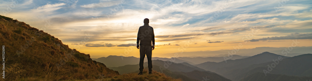 The man standing on the rock with a picturesque sunset