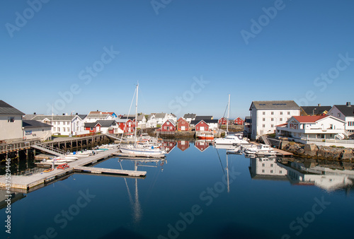 View of the port of Veiholmen, Smøla, Norway. Beautiful summery day with houses and boats reflected in the calm sea.