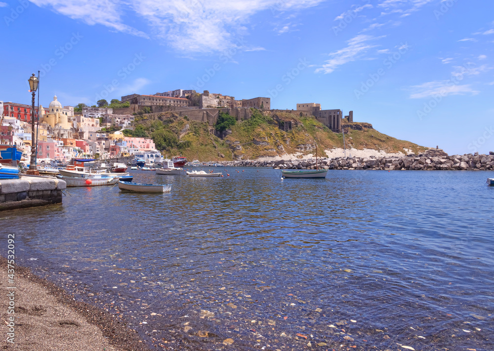 Panoramic view of beautiful of Procida, Italian Capital of Culture 2022: colorful houses, cafes and restaurants, fishing boats and yachts in Marina Corricella , in Gulf of Naples, Campania, Italy.