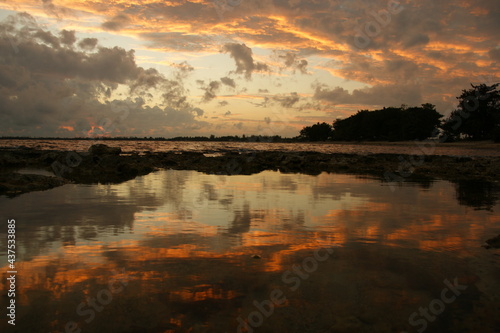 Storm clouds background. Dramatic sky at sunset with red, yellow and orange colors. The reflection of storm clouds in the sea enhances the effect