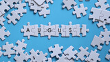 AUGUST word written on white jigsaw puzzle