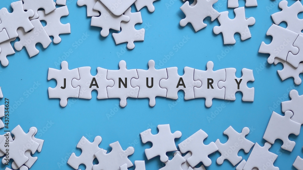 JANUARY word written on white jigsaw puzzle JANUARY word written on white jigsaw puzzle