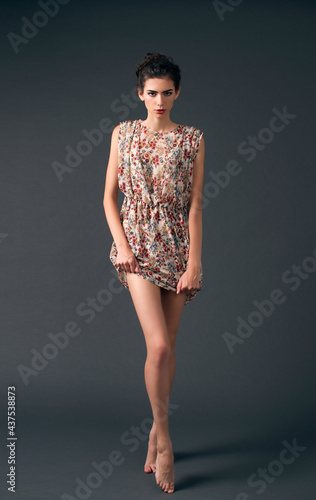 sexy leggy brunette in a dress posing against the backdrop of cyclorama
