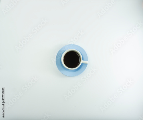 Hot coffee in a white ceramic cup with a blue glass base