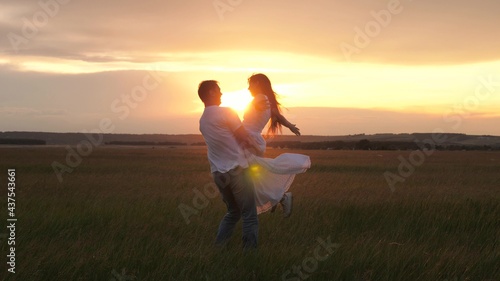 A lovely young couple enjoying time together and having fun dancing to celebrate their eternal love in sunshine on field. Happy love, family, loyalty. Free people have fun and dance in spring in park.