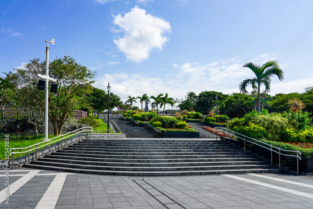 Naklejka premium 沖縄の青い空と青い海、海洋博公園の中央ゲートに至る美しい花壇のある石段