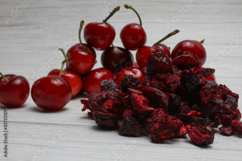 Fresh and freeze dried cherry on the light wooden background.