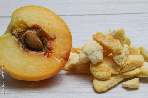 Fresh and freeze dried peach on the light wooden background.