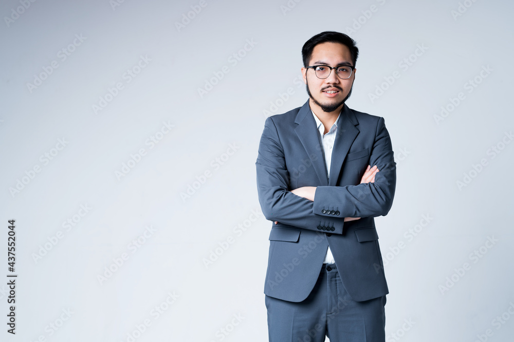 Serious stylish asian businessman in formal suit isolated on gray background with arms crossed on chest