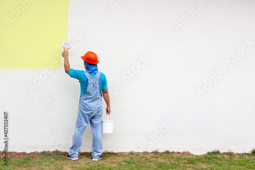 Rear view of painter man painting outdoor the wall,  isolated on big empty space