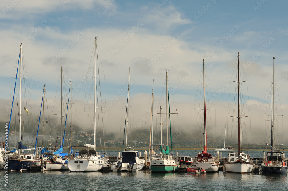 Yachts lying at anchor with mist forming on the Knysna Heads in the background