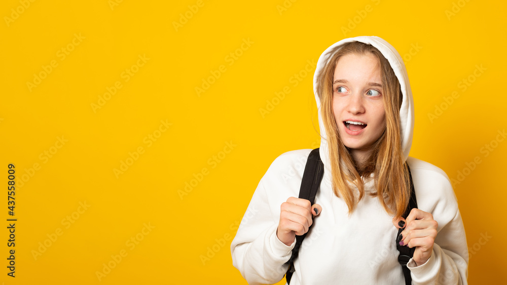 Banner. Cute adorable girl dressed white hoodie on yellow background with backpack. Portrait of cool schoolgirl with backpack. Banner. Cute adorable girl dressed white hoodie on yellow background with backpack. Portrait of cool schoolgirl with backpack.