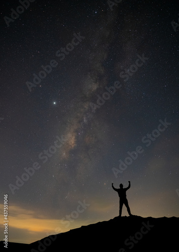 Tourist silhouette standing on the cliff on the background starry sky and the milky way. with noise and grain