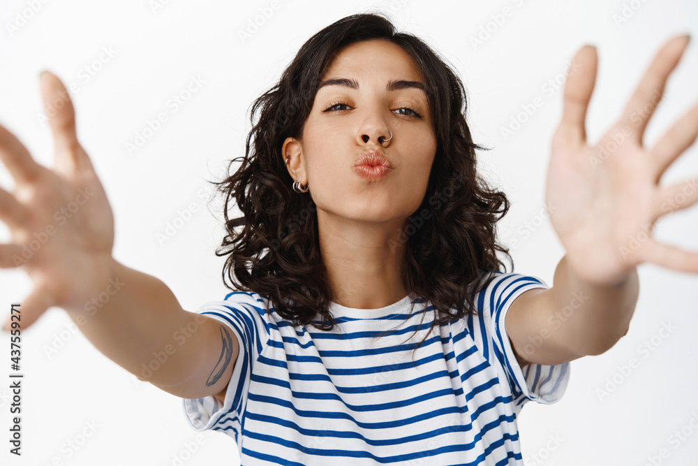 Cute brunette girl kissing you and reaching for hug, looking flirty at camera, pucker lips for kiss, standing in t-shirt against white background Cute brunette girl kissing you and reaching for hug, looking flirty at camera, pucker lips for kiss, standing in t-shirt against white background