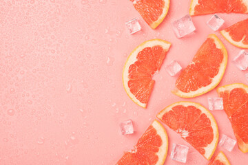 Top view photo of half slices grapefruit ice cubes and water drops on isolated pastel pink background with blank space