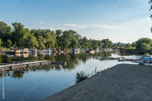 View of a floating summer houses intended for summer vacation with berths and a dock for boats and speedboats on the water surface of a river or lake © Srdjan