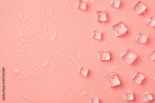 Top view photo of ice cubes on the right and drops on isolated pastel pink background with copyspace on the left photo