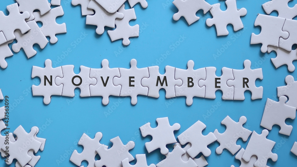 NOVEMBER word written on white jigsaw puzzle NOVEMBER word written on white jigsaw puzzle