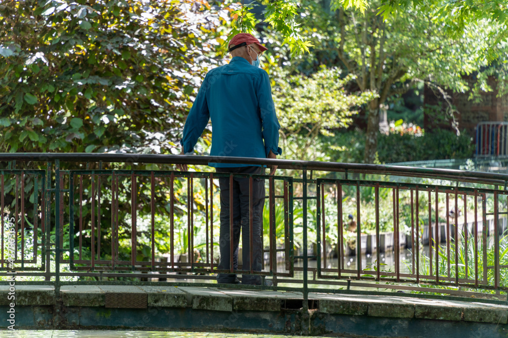 Man from behind admiring the scenery on a bridge, overlooking the river Man from behind admiring the scenery on a bridge, overlooking the river