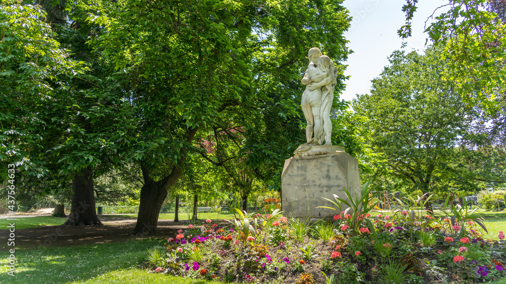 Pretty statues of a hugging couple, surrounded by trees and flowers Pretty statues of a hugging couple, surrounded by trees and flowers