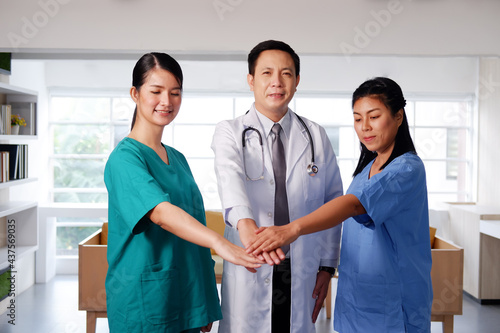 Asian chief physician man is holding hand with surgeon doctor women wears blue and green surgical gown together. Smiling Medical team in meeting room at hospital.