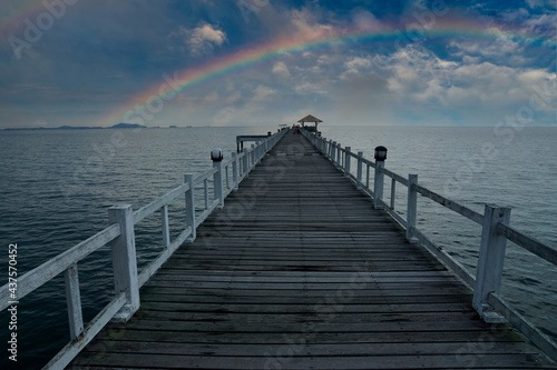 Wooden bridge in the sea, line leading the eye to the rainbow